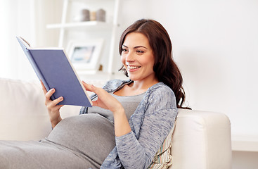 Image showing happy pregnant woman reading book at home