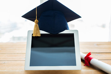 Image showing close up of tablet pc with mortarboard and diploma