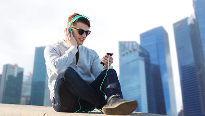 Image showing happy young man in headphones with smartphone