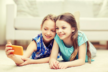 Image showing happy girls with smartphone taking selfie at home