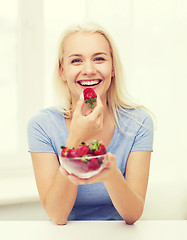 Image showing happy woman eating strawberry at home