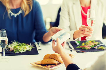 Image showing close up of women giving present at restaurant