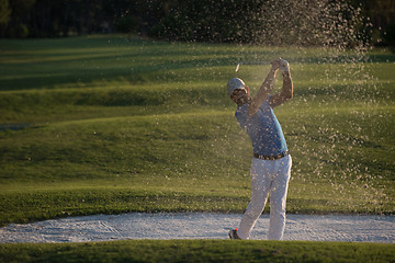 Image showing golfer hitting a sand bunker shot on sunset