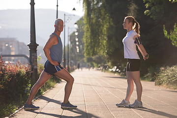 Image showing couple warming up and stretching before jogging