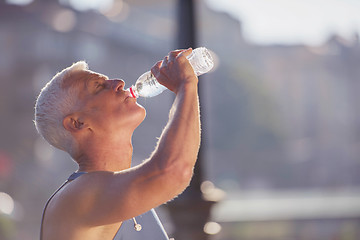 Image showing senior jogging man drinking fresh water from bottle