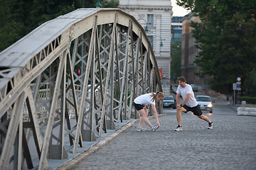 Image showing couple warming up and stretching before jogging