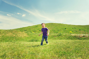 Image showing happy little boy running on green field outdoors