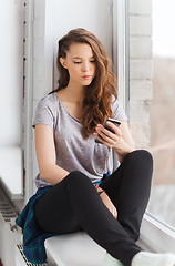 Image showing sad pretty teenage girl with smartphone texting