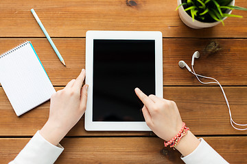 Image showing close up of woman with tablet pc on wooden table