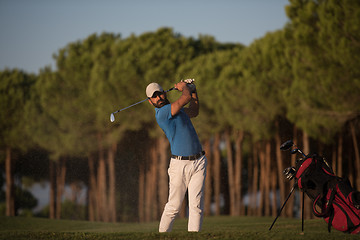 Image showing golfer hitting a sand bunker shot on sunset