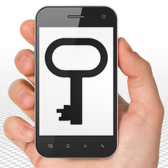 Image showing Protection concept: Hand Holding Smartphone with Key on display