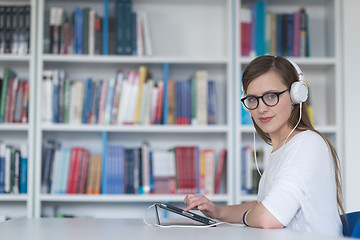 Image showing female student study in library, using tablet and searching for 