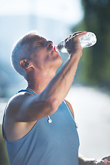 Image showing senior jogging man drinking fresh water from bottle