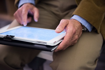 Image showing Closeup of mature hands holding tablet.