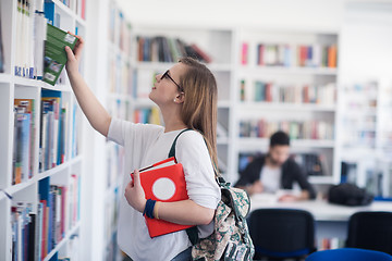 Image showing famale student selecting book to read in library