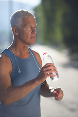 Image showing senior jogging man drinking fresh water from bottle