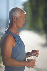 Image showing senior jogging man drinking fresh water from bottle