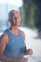 Image showing senior jogging man drinking fresh water from bottle