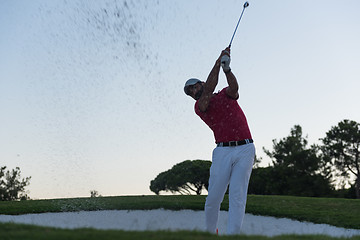 Image showing golfer hitting a sand bunker shot on sunset