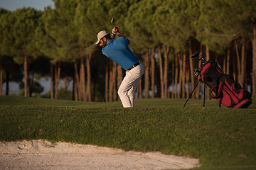 Image showing golfer hitting a sand bunker shot on sunset