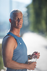 Image showing senior jogging man drinking fresh water from bottle