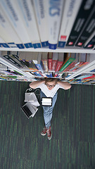 Image showing female student study in library, using tablet and searching for 