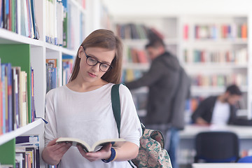 Image showing portrait of famale student reading book in library