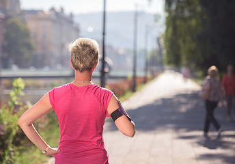 Image showing jogging woman setting phone before jogging