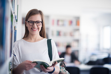 Image showing portrait of famale student reading book in library