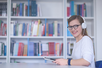 Image showing female student study in library, using tablet and searching for 