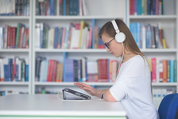 Image showing female student study in library, using tablet and searching for 