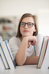 Image showing portrait of famale student selecting book to read in library