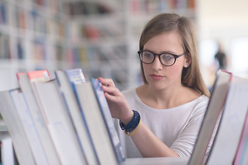 Image showing portrait of famale student selecting book to read in library