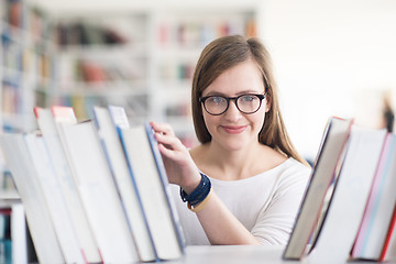 Image showing portrait of famale student selecting book to read in library