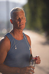 Image showing senior jogging man drinking fresh water from bottle