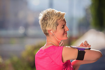 Image showing jogging woman setting phone before jogging