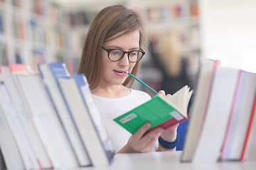 Image showing portrait of famale student selecting book to read in library