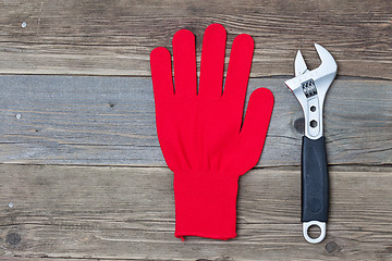 Image showing Red protective glove and an adjustable pipe wrench