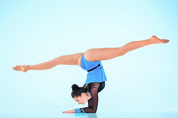 Image showing The girl doing gymnastics dance on a blue background