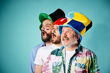 Image showing The three football fans singing the national anthem over blue