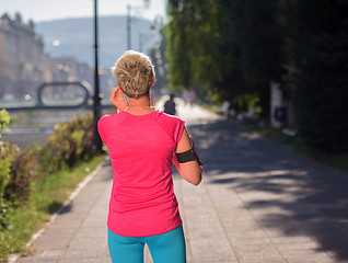 Image showing jogging woman setting phone before jogging