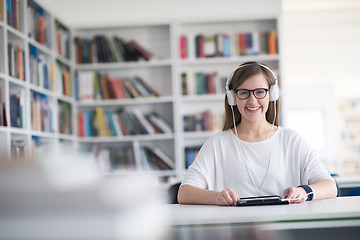 Image showing female student study in library, using tablet and searching for 