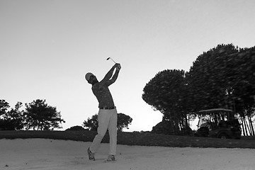 Image showing golfer hitting a sand bunker shot on sunset