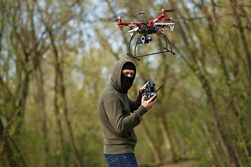 Image showing Man in mask operating a drone with remote control.