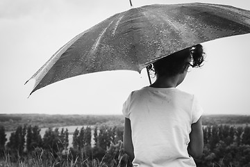 Image showing girl sitting in the pouring rain with an umbrella