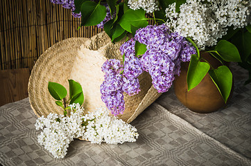 Image showing Still-life with a bouquet of lilacs and a straw hat, close-up