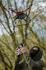 Image showing Man in mask operating a drone with remote control.