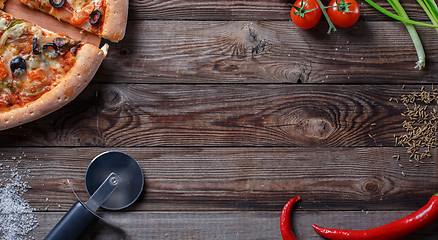 Image showing Tasty pizza with ingridients on a wooden board.