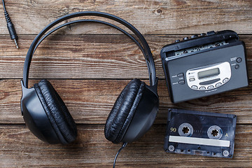 Image showing Headphones, player and retro compact cassette over wooden background. Top view