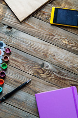 Image showing Watercolors, color pencils and sketchbook on wooden table. Flat lay photo with empty space for logo, text.